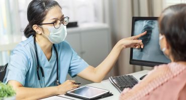 Asian,Female,Doctor,In,Medical,Mask,Examining,And,Pointing,To Radang Paru-paru